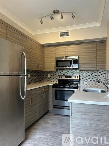 A kitchen with a refrigerator, microwave, oven, and sink.