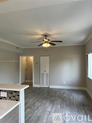 A room with a ceiling fan and a tiled counter.