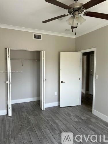 A room with a ceiling fan and a doorway leading to another room.