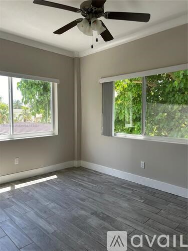 A room with a ceiling fan and two windows.
