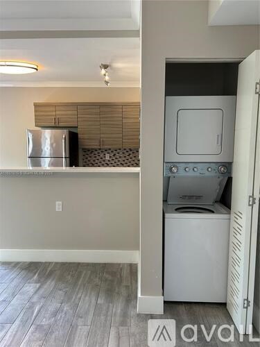 A small white washing machine is in a cabinet in a room with a white wall.