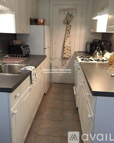 A kitchen with white cabinets and a black countertop.