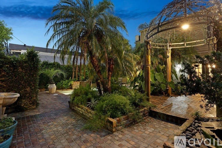A garden with a brick pathway and a palm tree.