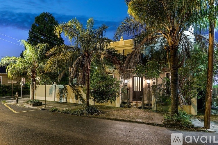 A house with a lit up front porch and a tree in front.