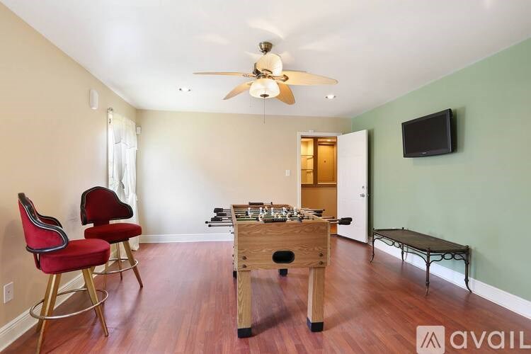 A room with a red chair and a wooden table with a foosball table in the middle.