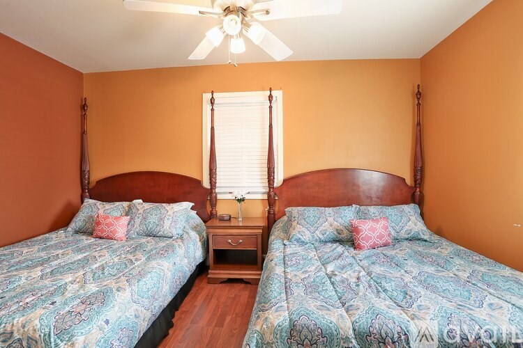 Two twin beds with blue bedspreads in a room with orange walls.