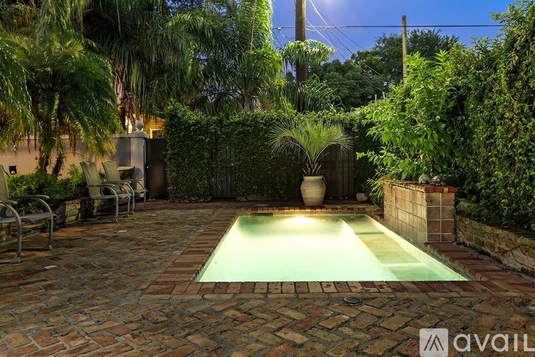 A backyard with a pool surrounded by green plants.