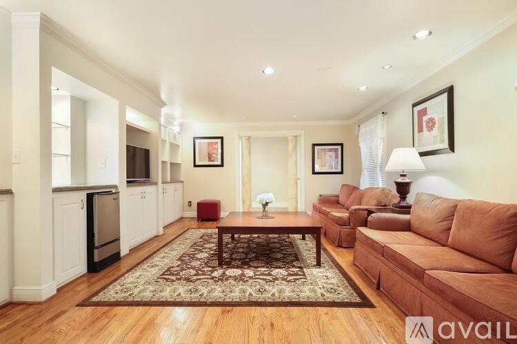 A living room with a brown couch and a rug.