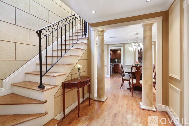 A wooden staircase with a metal railing leads to a dining area.