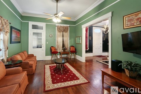 A living room with a red rug and a brown sofa.