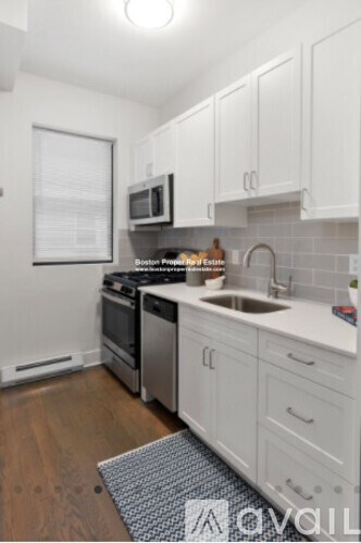 A kitchen with white cabinets and a black and white rug on the floor.