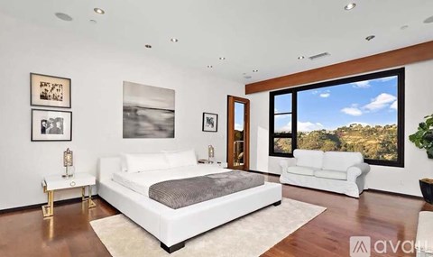 A bedroom with a large bed and a view of the outdoors through a window.