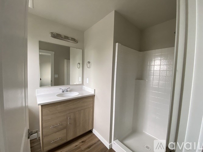 A bathroom with a sink, mirror, and a walk-in shower.