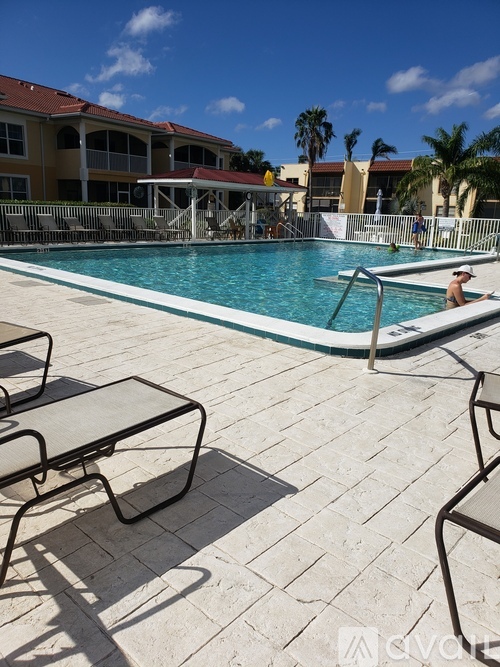 A pool with a person in it and chairs around it.
