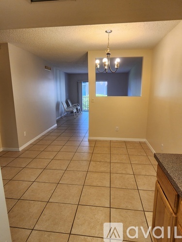 A spacious room with tile flooring and a chandelier.