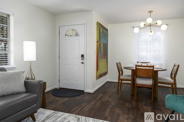 A living room with a grey couch, a wooden dining table and chairs, and a painting on the wall.