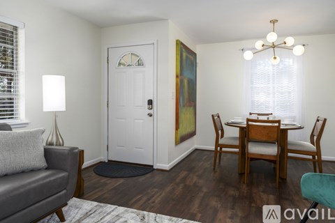A living room with a grey couch, a wooden dining table and chairs, and a painting on the wall.