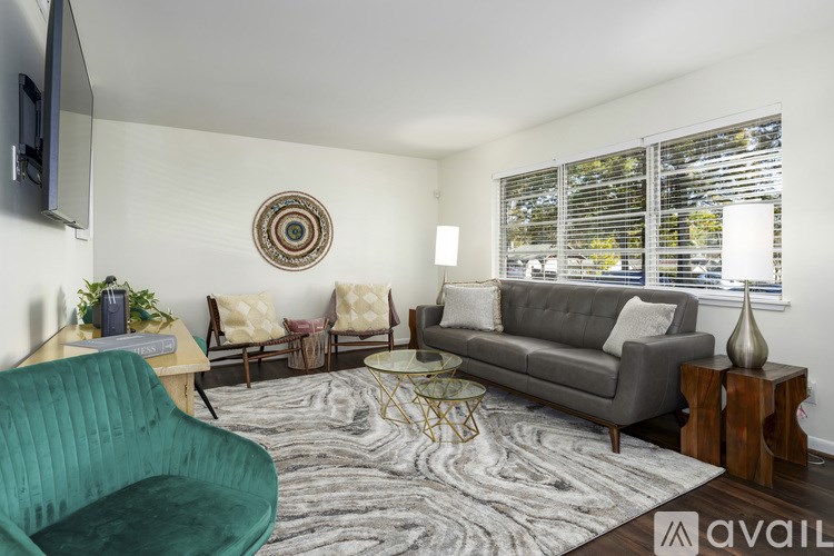 A living room with a green chair, a grey couch, and a wooden side table.