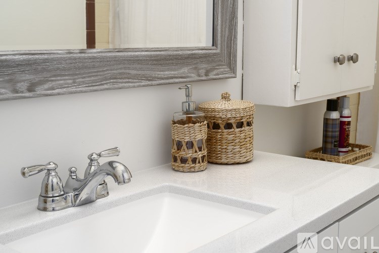 A bathroom sink with a silver faucet and two wicker baskets on the counter.