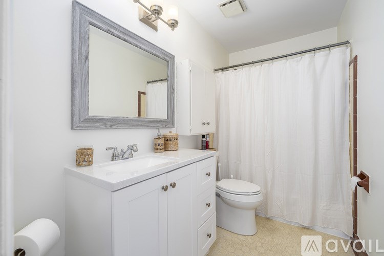 A bathroom with a white toilet, sink, and shower curtain.