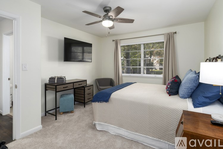 A bedroom with a bed, desk, and window.