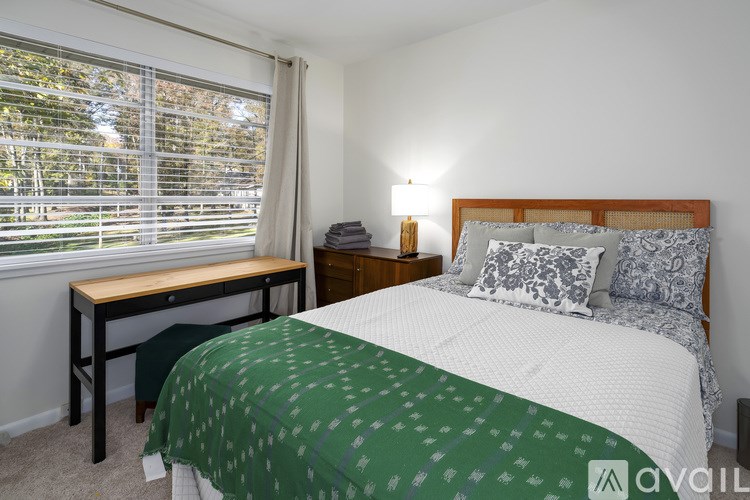 A bedroom with a bed, desk, and window.