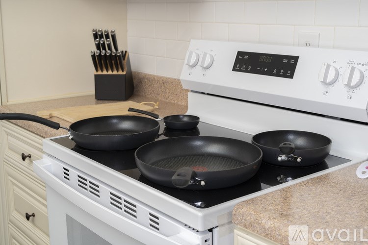 A white stove with four burners and a digital display, with pans on the front burner.