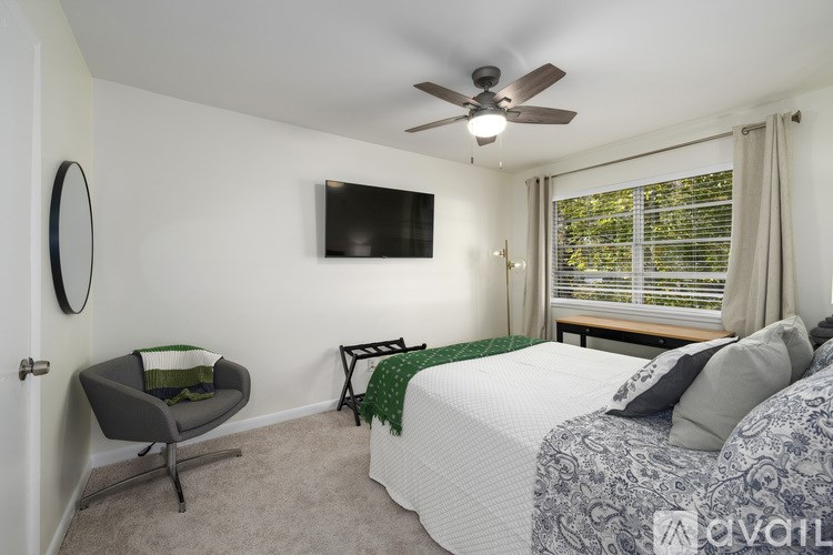 A bedroom with a bed, chair, and a ceiling fan.