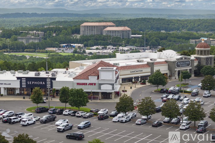 A parking lot with cars and a shopping center in the background.