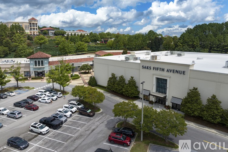 A parking lot with cars and a building that says Saks Fifth Avenue.