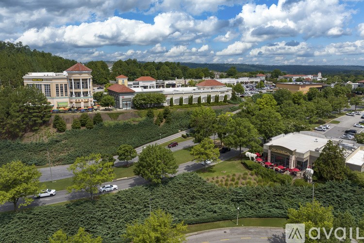 A large building with a red roof is surrounded by trees and a parking lot.