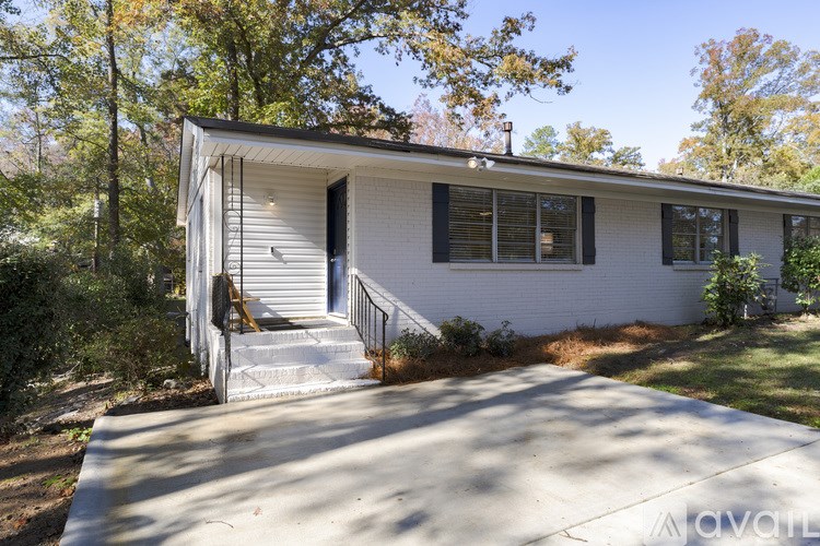 A small white house with a porch and a driveway in front.