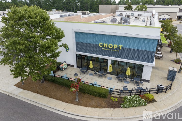 A Chopt storefront with a green tree in front.