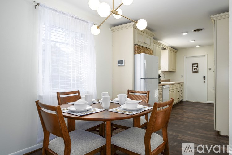 A dining room with a table set for two and a kitchen in the background.
