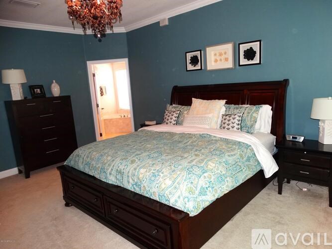 A bedroom with a large bed and a chandelier.