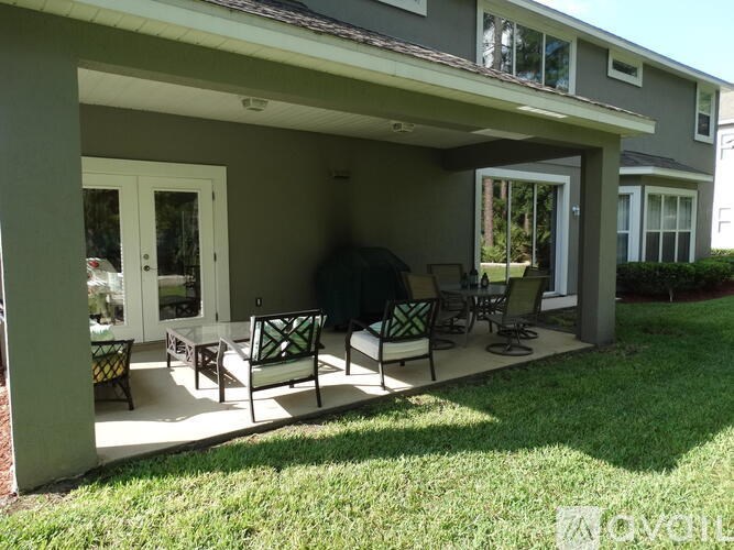 A patio with a table and chairs is covered by a roof.