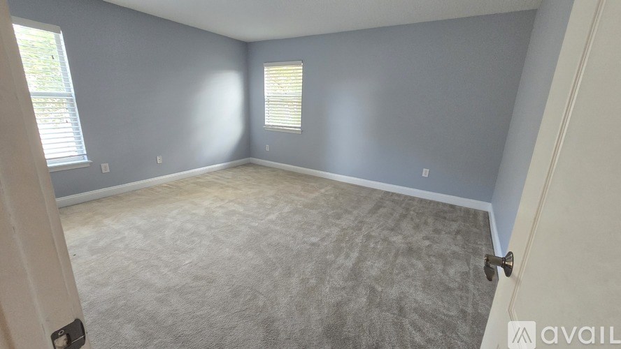 A room with a carpeted floor and a window with blinds.
