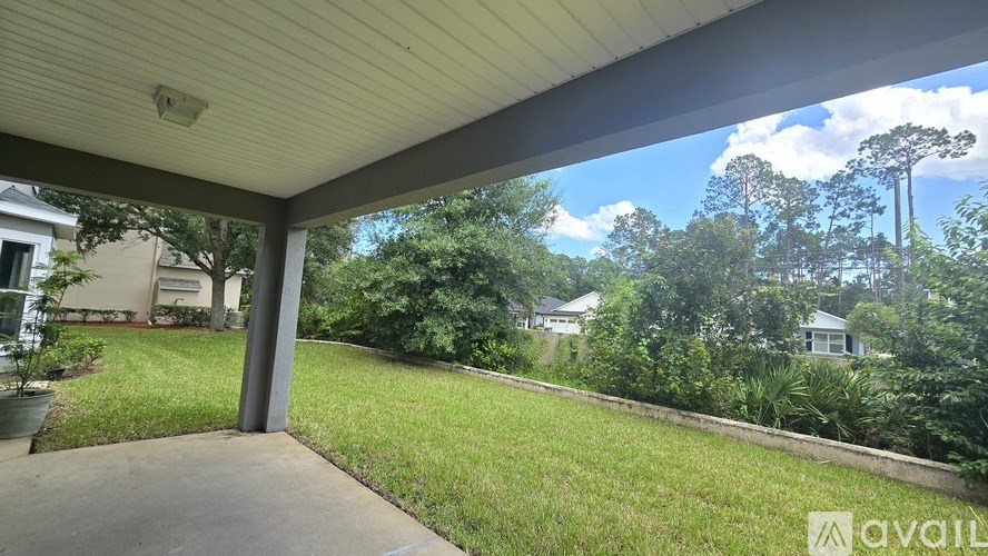 A porch with a view of a green yard and trees.