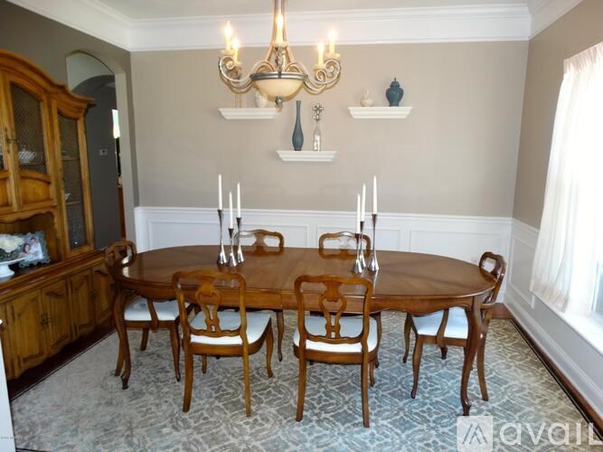 A wooden dining table with chairs and a chandelier in a room.