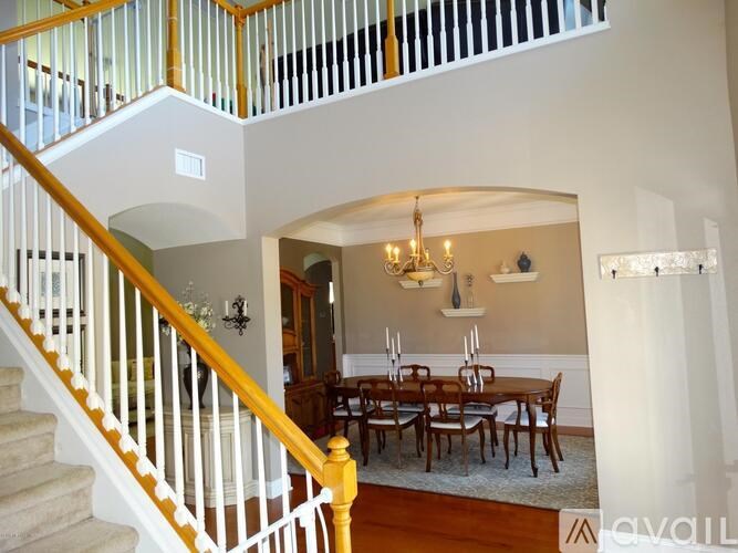 A staircase with a yellow railing leads to a dining room with a wooden table and chairs.