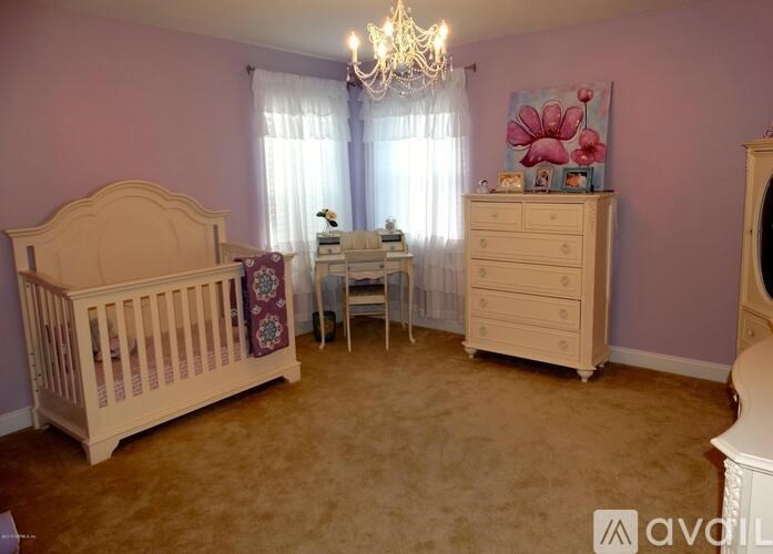 A baby room with a crib, a dresser, and a chandelier.