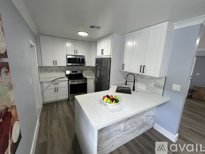 A kitchen with white cabinets and a marble countertop.