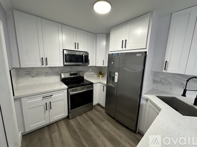 A kitchen with white cabinets and a marble countertop.