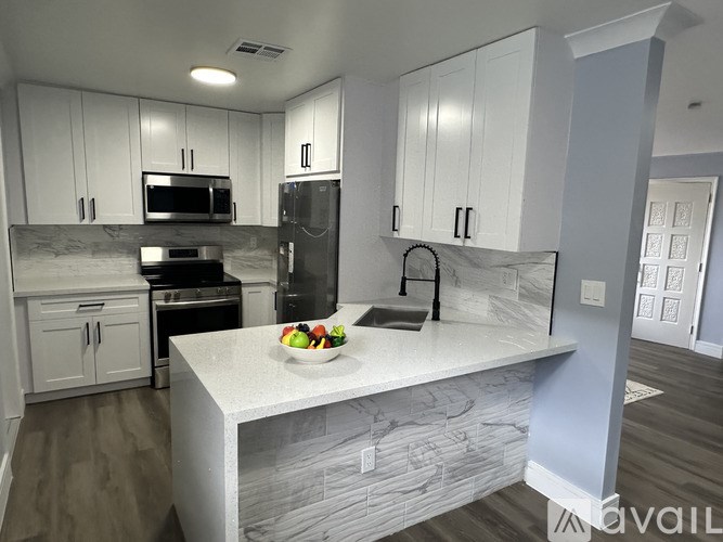 A kitchen with white cabinets and a marble island.