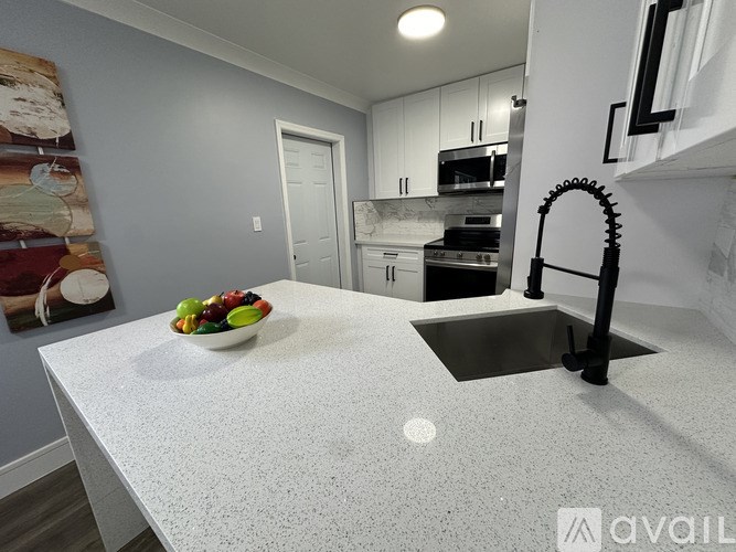 A kitchen with a white countertop and a bowl of fruit on it.