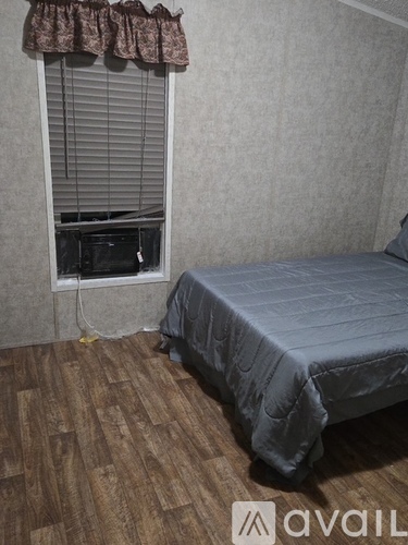 A bedroom with a bed and a window with a curtain.