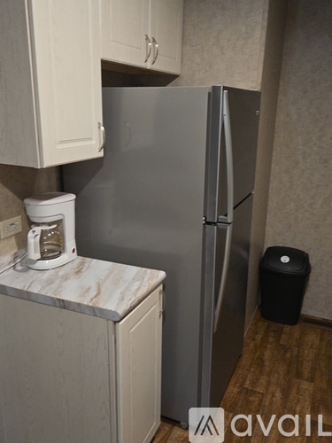 A kitchen with a refrigerator, a toaster, and a trash can.