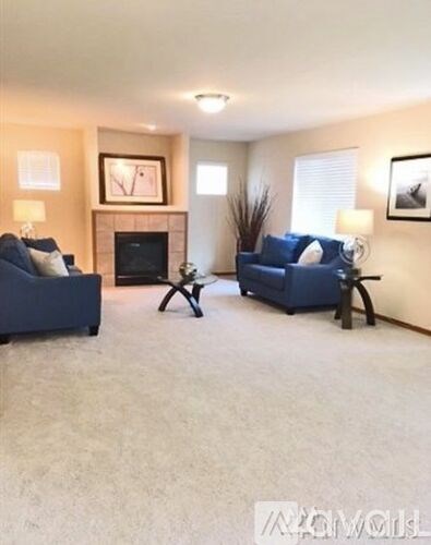 A living room with a fireplace and two blue couches.