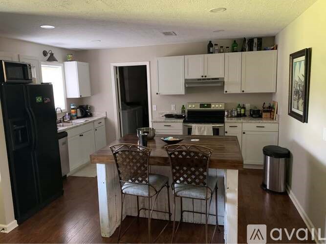 A kitchen with a black fridge and white cabinets.