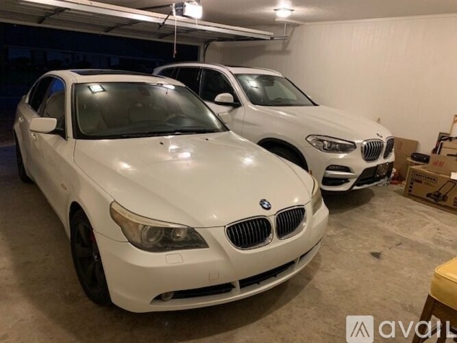 Two white BMW cars are parked in a garage.